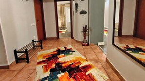 Un couloir agrémenté d’un tapis coloré, d’un banc, d’un miroir et d’une plante.