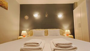 Une chambre d’hôtel avec un grand lit, deux lampes de chevet, une armoire et un luminaire fixé au mur.