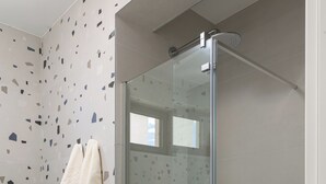 Een moderne badkamer met een douchecabine van glas, een potplant en een handdoekhouder.