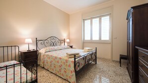 A bedroom with a bed, bedside tables, a wardrobe, and a window with blinds. - VILLIN0 DEI PINI - Relaxation in Salento (Puglia)