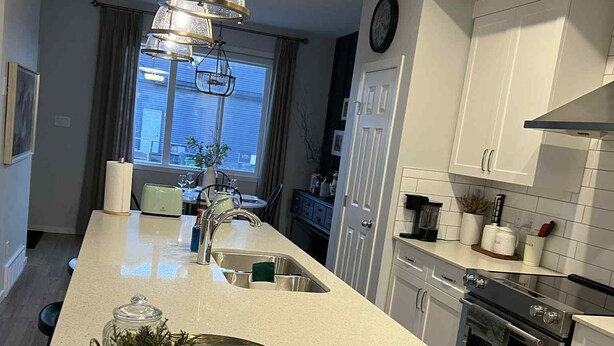 Een moderne keuken met een centraal eiland, roestvrijstalen apparatuur en een hanglamp.