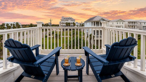 Eine Terrasse mit zwei Stühlen und einem Tisch, mit Blick auf eine Wohngegend mit Häusern und blauem Himmel.