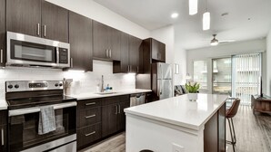 Una cocina moderna con armarios de madera oscura, electrodomésticos de acero inoxidable y encimera blanca.