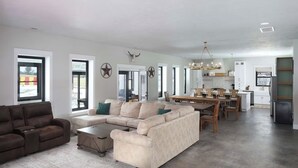Un grand salon comprenant un canapé, une table basse et une table à manger. Les murs sont décorés de motifs en forme d’étoiles et un lustre est suspendu au-dessus de la table à manger.