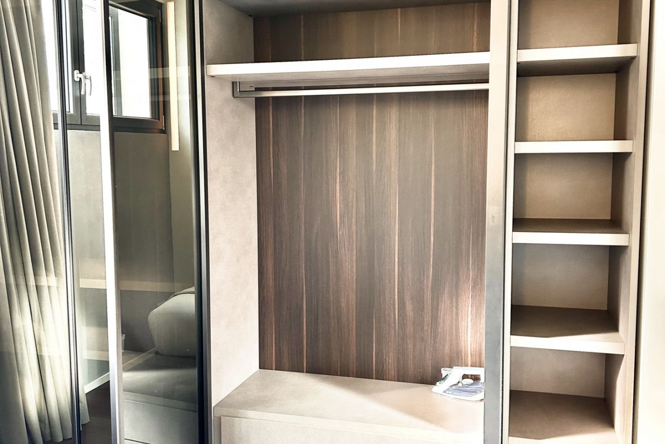 A walk-in closet with a sliding door, a wooden panel wall, and a shelving unit.