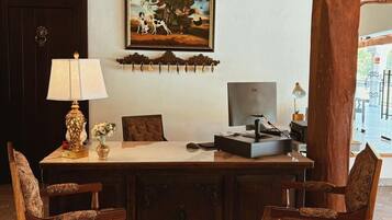 A room with a desk, two chairs, a clock, a framed picture, and a large wooden column.