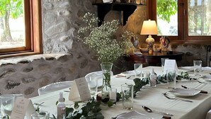 Un espace repas avec un mur en pierre, un plafond en bois et une table dressée pour le repas.