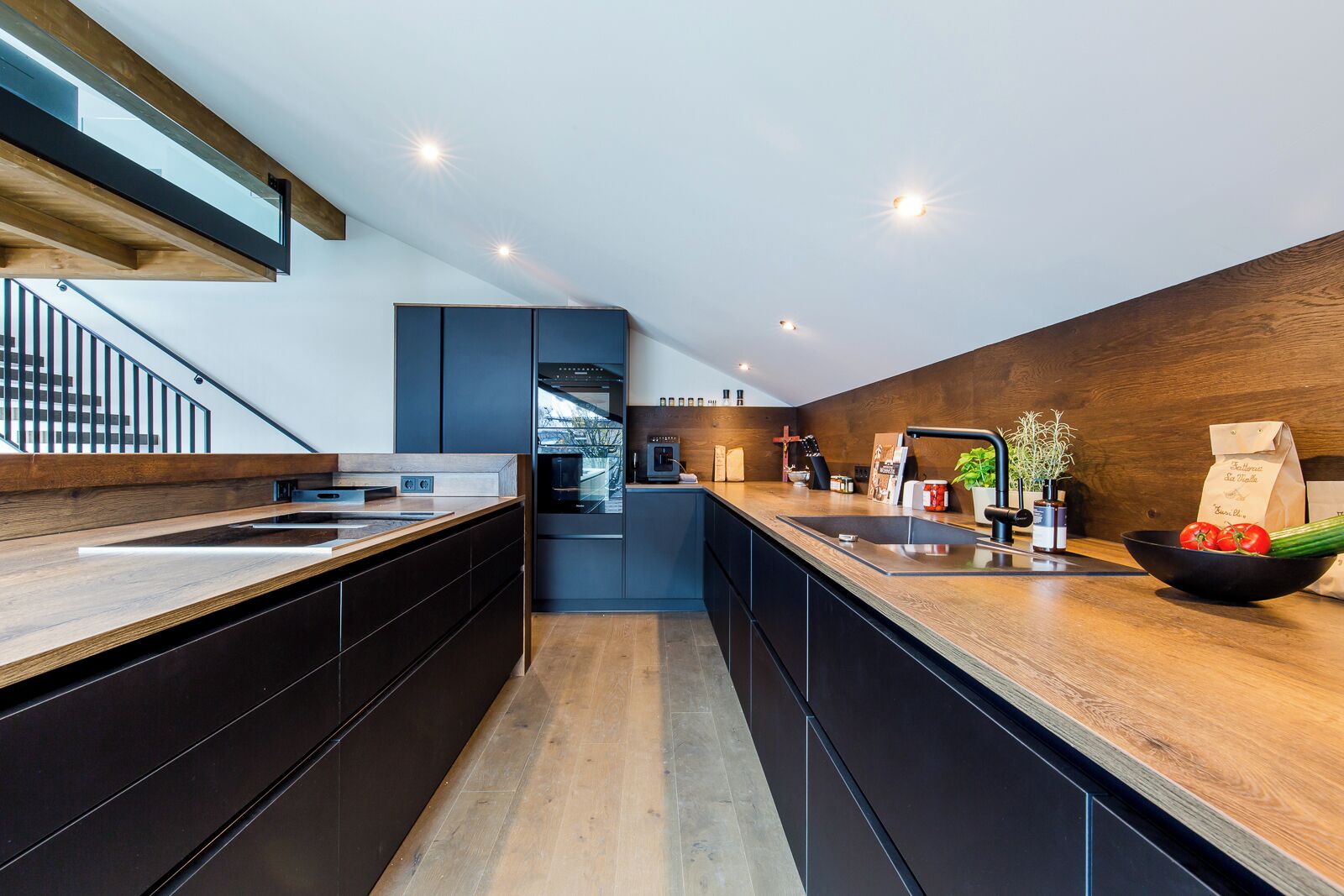 Een moderne keuken met een houten aanrechtblad, ingebouwde apparatuur en uitzicht op buiten.