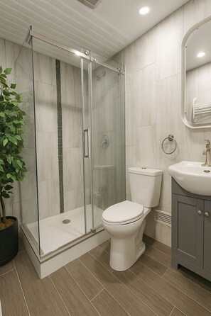 A modern bathroom with a glass-enclosed shower, a toilet, and a sink.