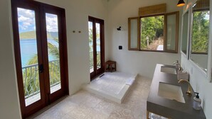Ein Badezimmer mit großem Fenster, Waschbecken und Spiegel.