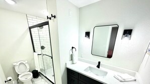 Une salle de bain moderne équipée de toilettes, d’une douche, d’un lavabo et d’un miroir.