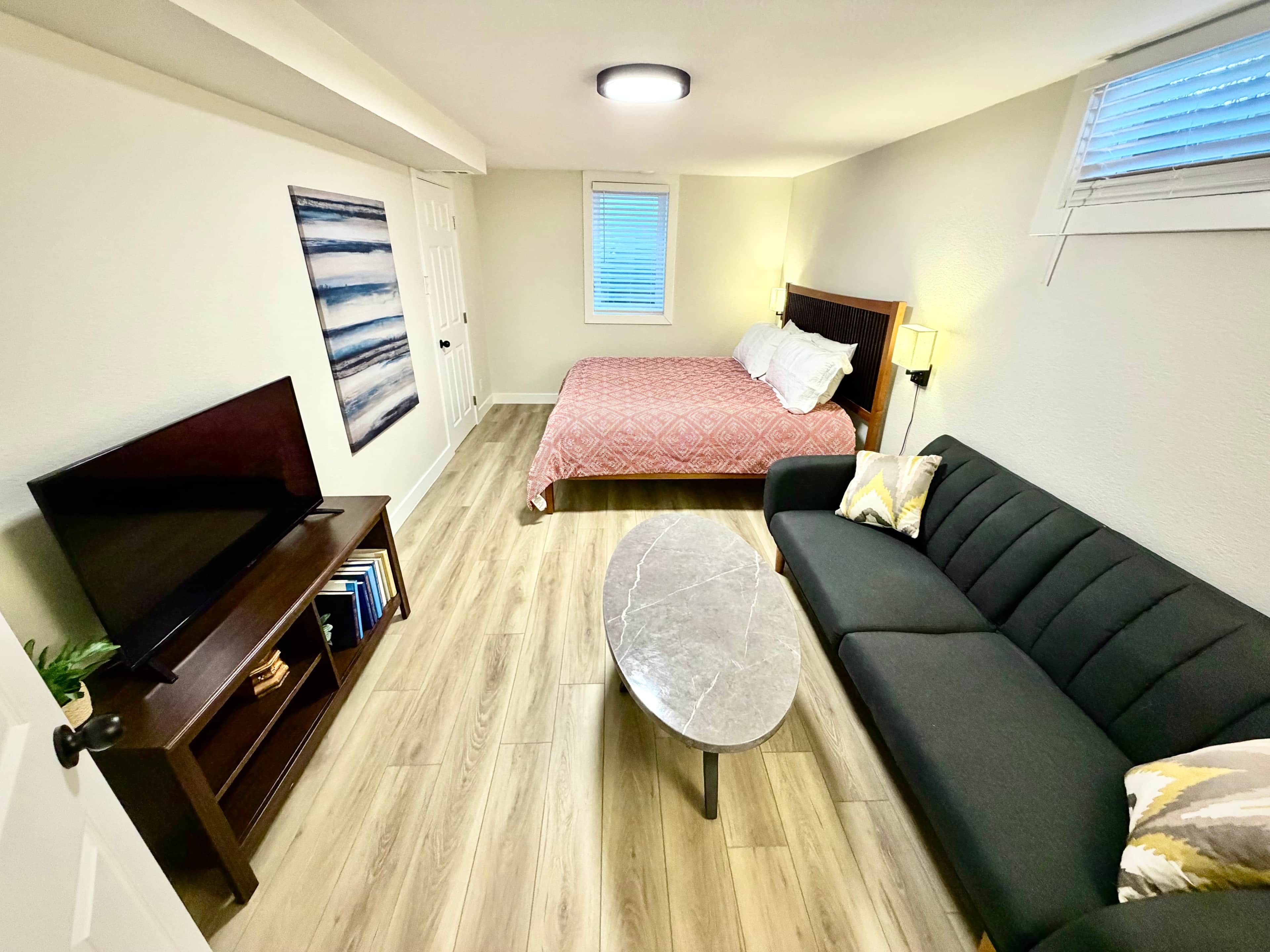 A compact living space with a bed, a sofa, a TV, and a small table.