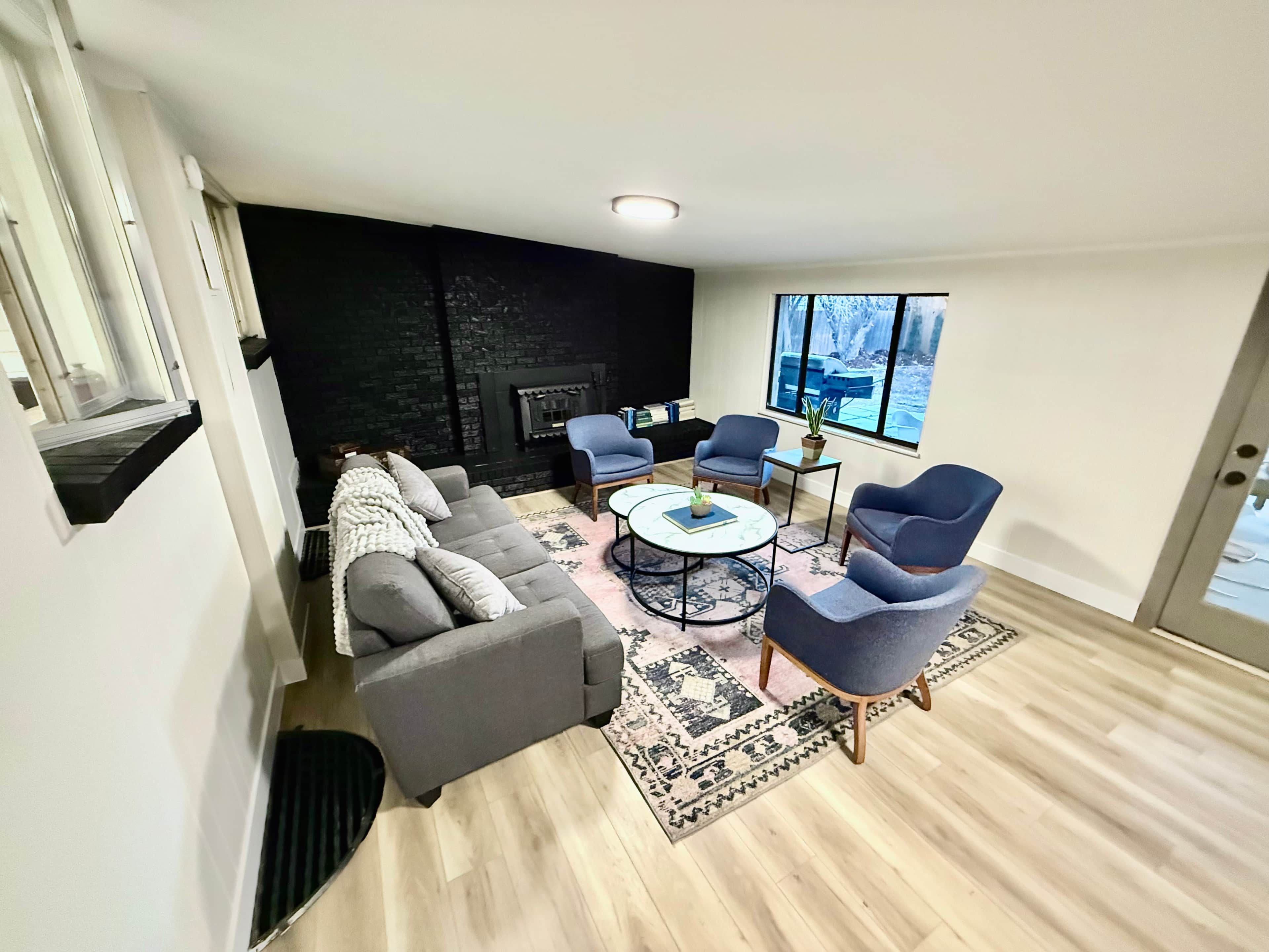 A modern living room with a grey sofa, two armchairs, a coffee table, and a fireplace.