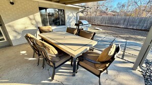 Une terrasse extérieure avec une table et des chaises, un barbecue et une vue sur le jardin.