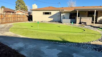 A residential backyard with a lawn, a hot tub, and a wooden fence.