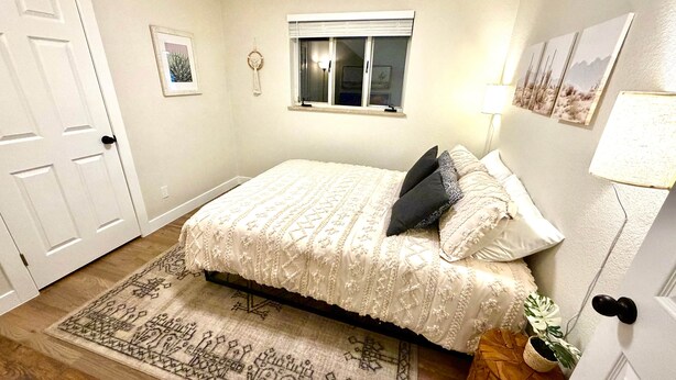 Une chambre à coucher avec un lit, une fenêtre, une lampe fixée au mur et une porte.