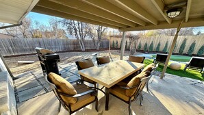 Une terrasse extérieure avec une table et des chaises, un barbecue et un espace abrité.