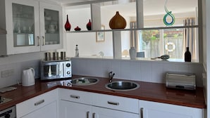 Een moderne keuken met witte kastjes, roestvrijstalen apparatuur en een houten aanrecht.