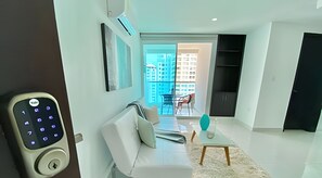 Ein modernes Wohnzimmer mit einer Couch, einem Couchtisch und Blick auf einen Balkon mit Hochhäusern.