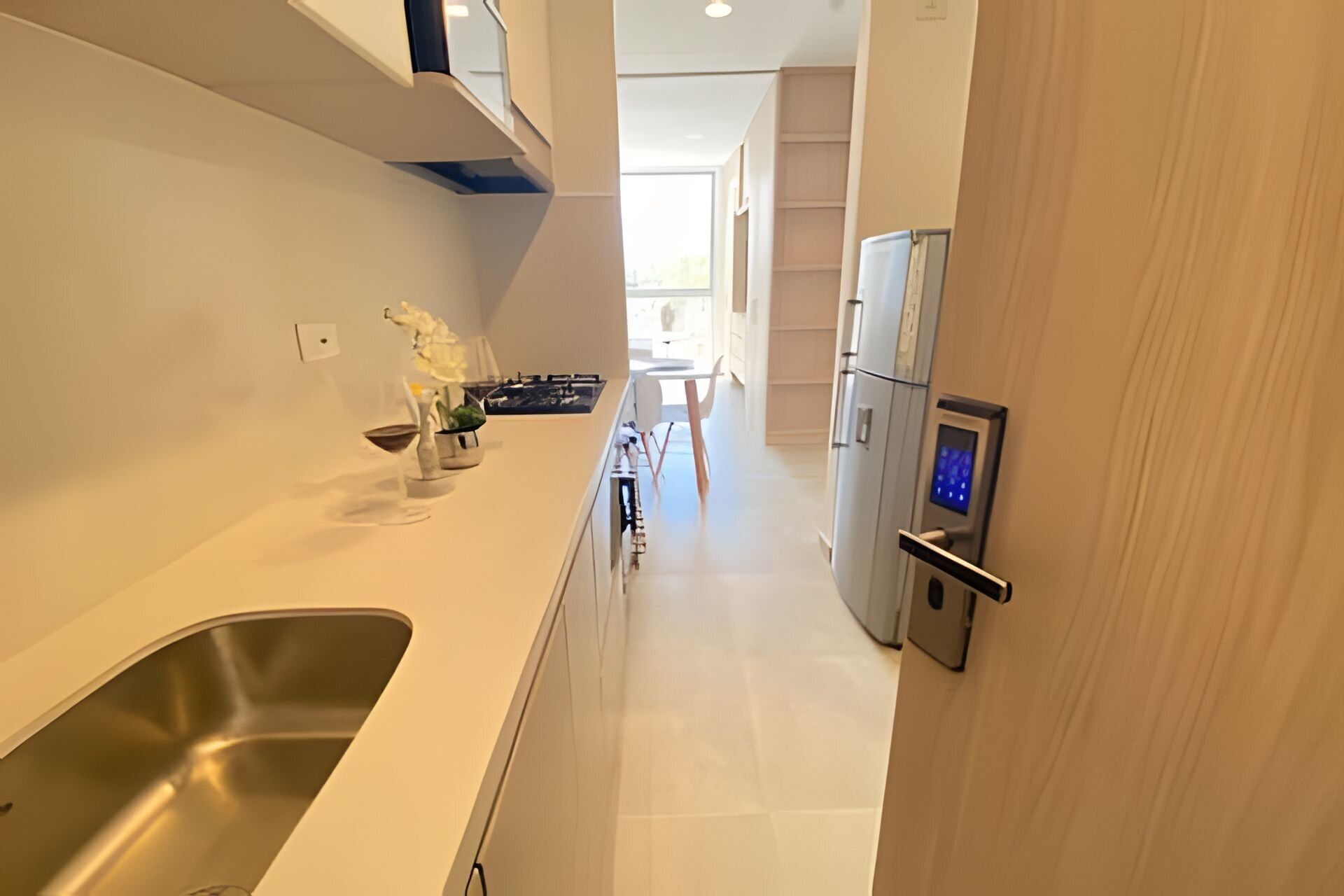Una cucina moderna con lavello in acciaio inossidabile, frigorifero con interfaccia digitale e zona pranzo con tavolo e sedie.