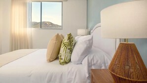 Une chambre d’hôtel avec un lit, une fenêtre donnant sur un paysage agréable, une lampe et une table de chevet.