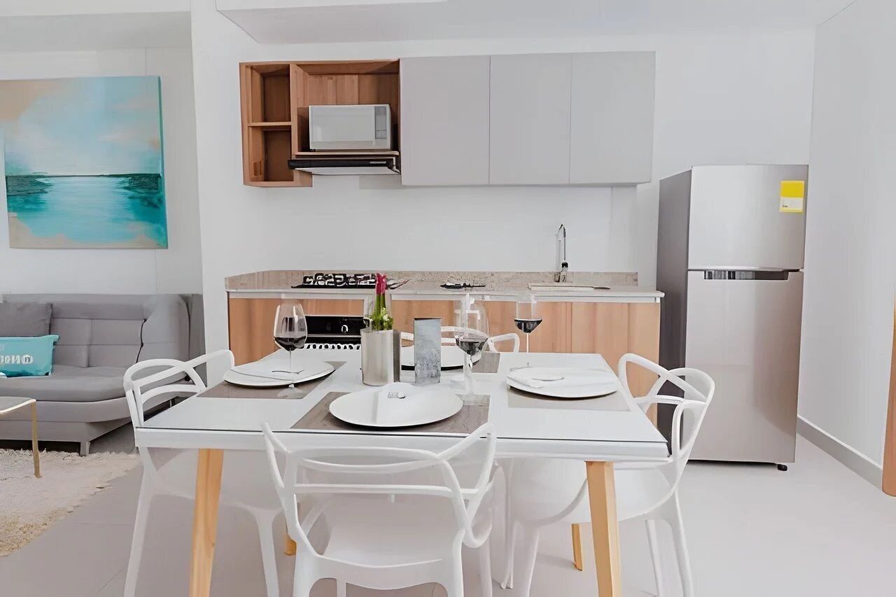 A modern kitchen with white cabinetry, a built-in microwave, and a stainless steel refrigerator.