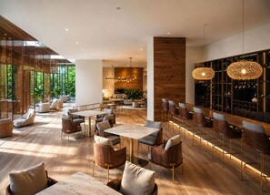 Ein modernes Interieur mit Barbereich, Sitzgelegenheiten und Blick auf Grünflächen.