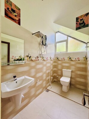A bathroom with a sink, toilet, shower, and a window.