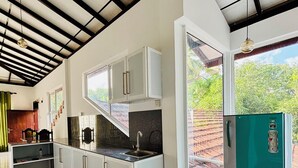 Una cocina moderna con armarios blancos, encimera negra y refrigerador verde.