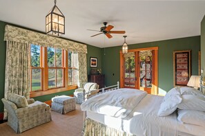 A bedroom with a large bed, a chair, a small table, a ceiling fan, and a window with curtains. - High Rock Ranch | The Luxury Private Estate in Yorkville (Yorkville)