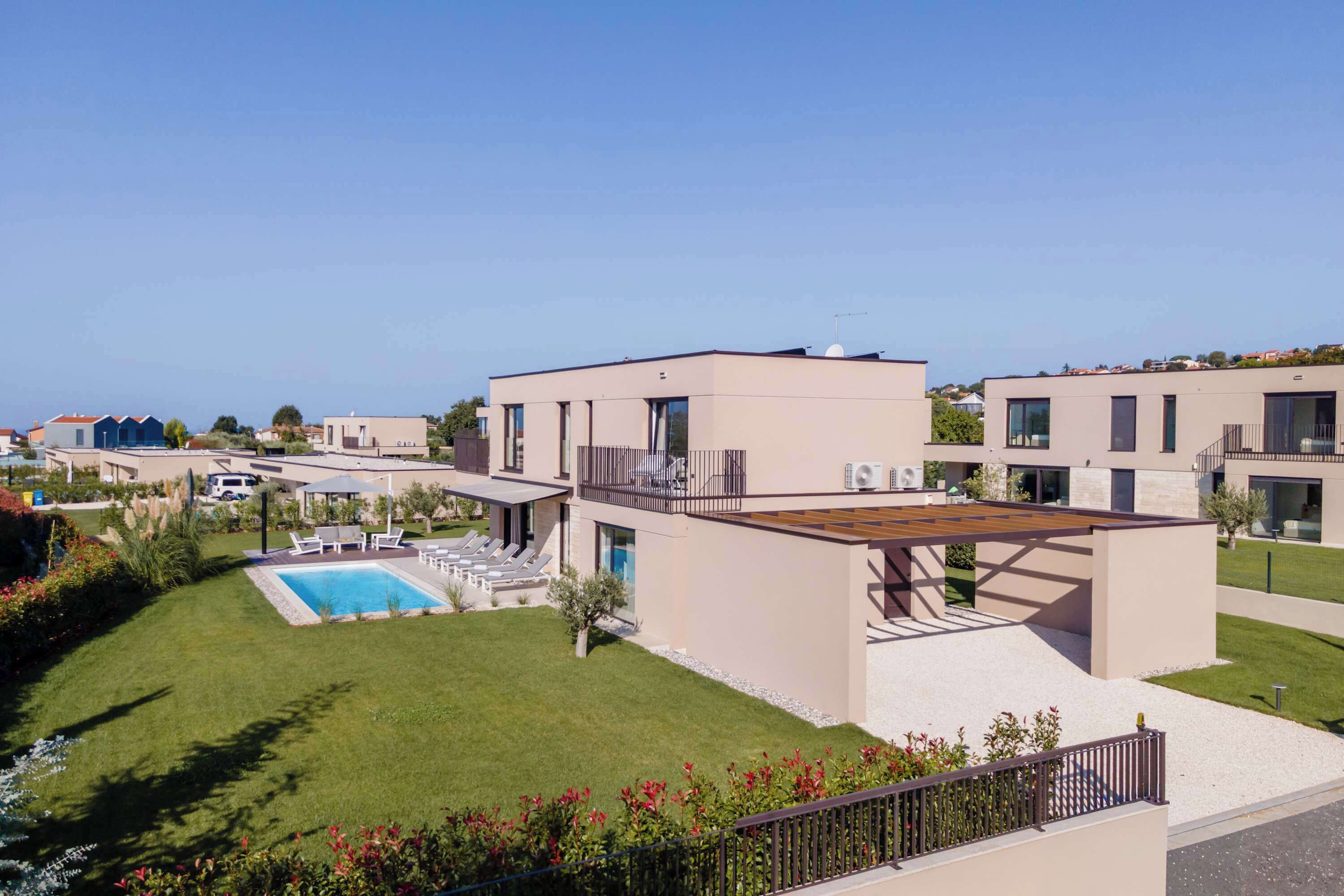 A modern residential building with a swimming pool, a covered patio, and a well-maintained lawn.