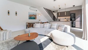 A modern living room with a sectional sofa, a coffee table, and a staircase leading to a kitchen. - Villa Vegt - Luxury villa close to Porec (Labinci)