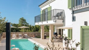 Ein zweistöckiges Gebäude mit Schwimmbad, Sitzgelegenheiten im Freien und einem Balkon.