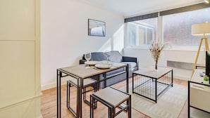 Een moderne woonkamer met een eethoek, een bank, een salontafel en een lamp.