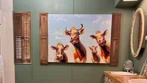 Een badkamer met houten vloeren, een wastafel, kastjes en een spiegel aan de muur.
