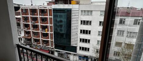 A balcony with a view of a cityscape, including buildings and a street.