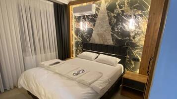 Una cama bien hecha con edredón blanco y almohadas, un cabecero de madera con diseño tipo mármol y un equipo de aire acondicionado montado sobre la cama.