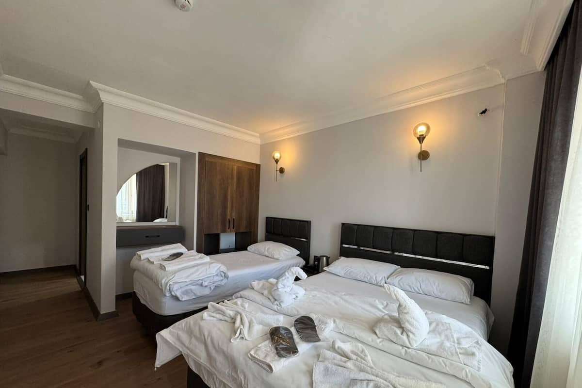 A hotel room with two beds, a wardrobe, a mirror, and two wall-mounted lights.