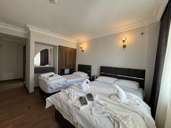 A hotel room with two beds, a wardrobe, a mirror, and two wall-mounted lights.