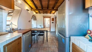 Une cuisine de taille réduite avec un plafond en bois, un réfrigérateur en acier inoxydable et une table à manger avec des chaises.