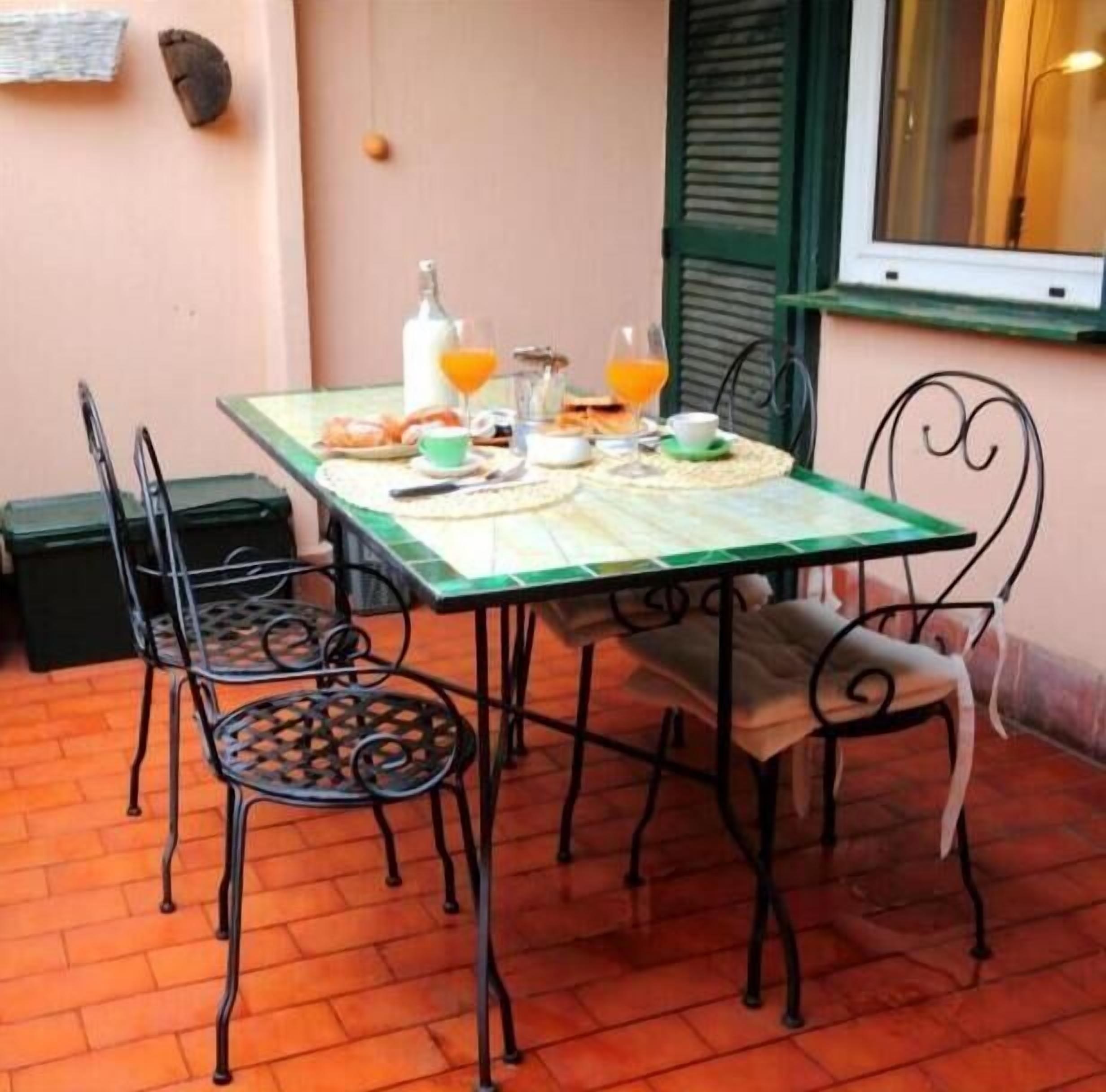Uma mesa de jantar com cadeiras, uma garrafa, copos e alimentos.