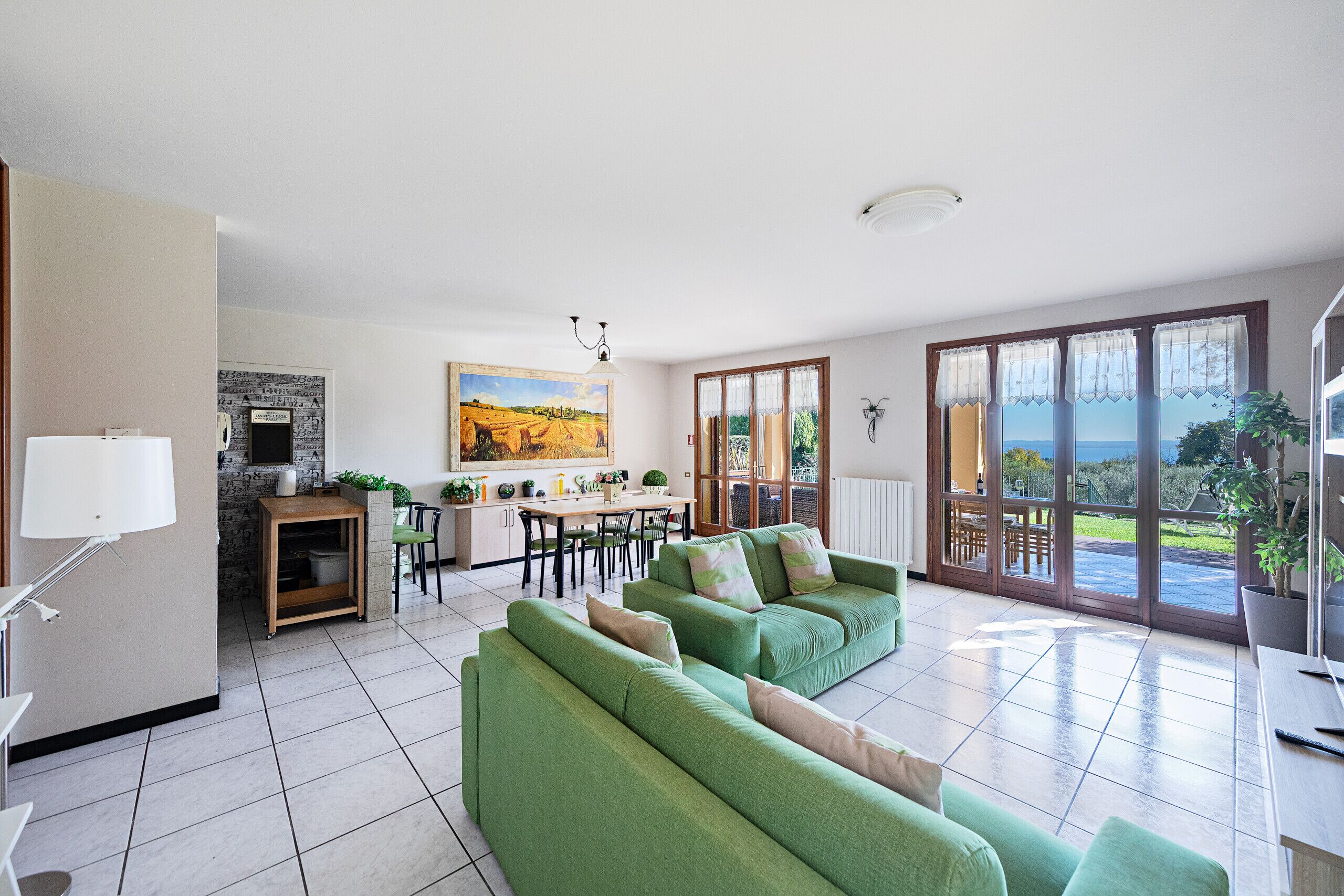 Ein modernes Wohnzimmer mit grünen Sofas, einem Essbereich und einer Küche.
