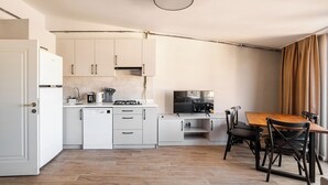 A modern kitchen with white cabinetry, a built-in dishwasher, and a dining area with a wooden table and black chairs. - Modern Penthouse w/ Private Terrace Near Metro (istanbul)