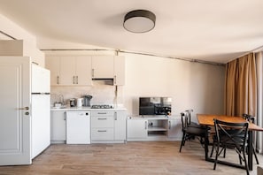 Eine moderne Küche mit weißen Schränken, einem integrierten Geschirrspüler und einem Essbereich mit einem Holztisch und schwarzen Stühlen.