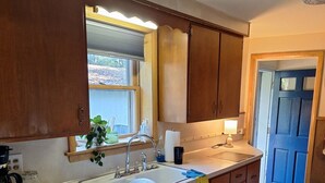 Una cucina con mobili in legno, un piano di lavoro bianco, una lavastoviglie e una finestra con persiane.