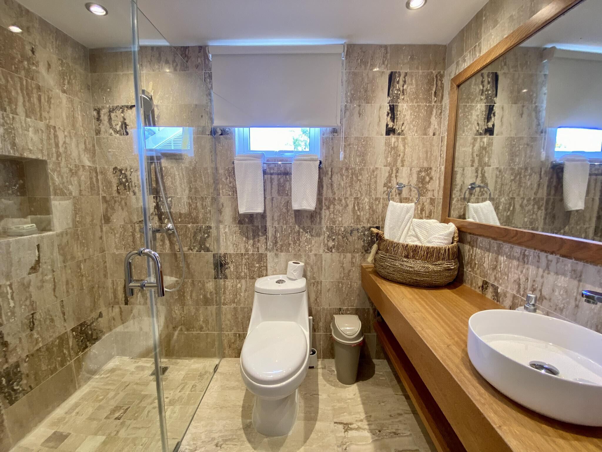 A modern bathroom with a glass-enclosed shower, a toilet, and a vanity with a sink.