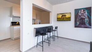 A modern kitchen with a built-in oven and a dining area with a black bar and chairs. - Aurelius - Superior sea view apartment (Konavle)