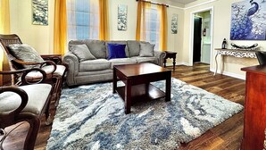 Una sala de estar con sofá, sillones, una mesa de centro y un tapete estampado.