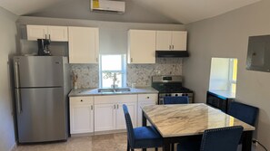 A compact kitchen with white cabinets, a stainless steel refrigerator, a gas stove, and a marble countertop. - Stay at historical property in St Croix, r/t Alexander Hamilton grew up! (Christiansted)