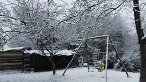 Ein verschneiter Garten mit Schaukel und Holzzaun.